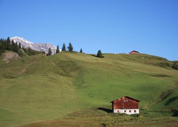 House on mountain against clear blue sky