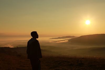 Silhouette man standing on mountain against sky during sunrise