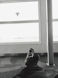 Low section of man sitting on window