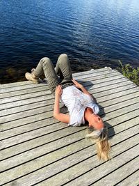 High angle view of woman lying on pier over lake