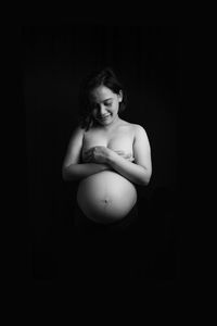 Young woman looking away against black background