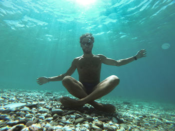 Portrait of shirtless man sitting undersea