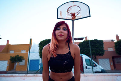 Portrait of young woman standing against sky