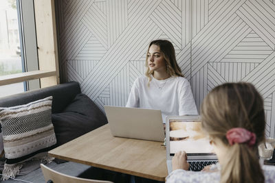 Female friends working on laptop while sitting in cafe