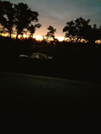 Silhouette trees on landscape against sunset sky