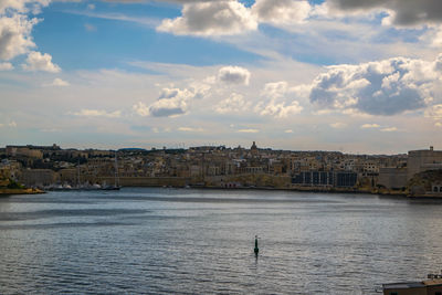 View of buildings by sea against cloudy sky