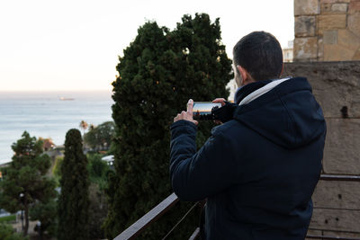 Man taking pictures of the seascape with his phone