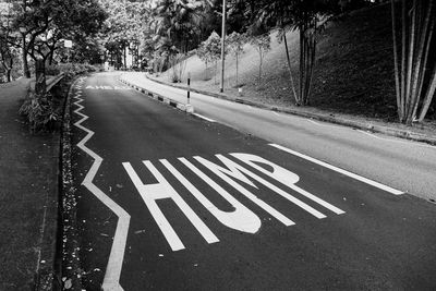 Road sign by trees on street in city