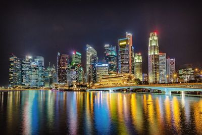 Illuminated cityscape against calm sea at night