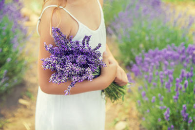 Midsection of woman standing on purple flowering plant