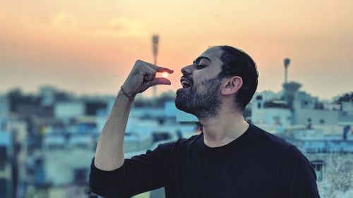 Man with camera against sky during sunset