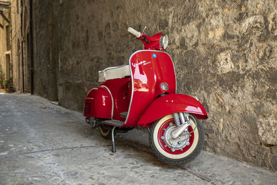 Red motor scooter against wall in city