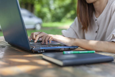 Midsection of woman using laptop at table