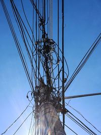 Low angle view of electricity pylon against clear blue sky