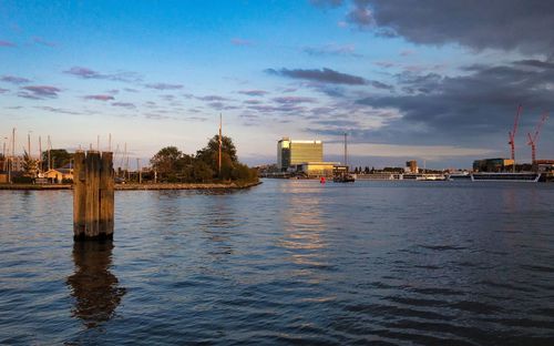 River by buildings in city against sky at dusk
