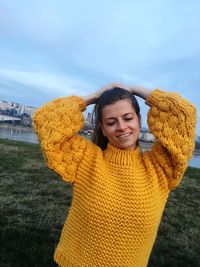 Smiling young woman looking down on grass against sky