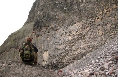 Rear view of man sitting on rock formation