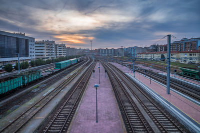 Railroad tracks in city against sky during sunset