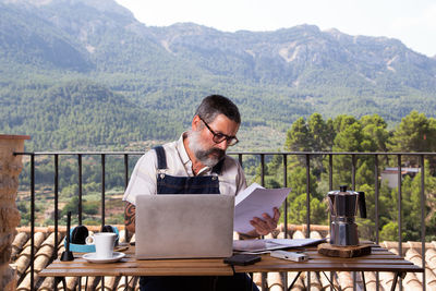 Man using mobile phone while sitting on table