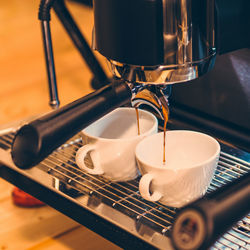 Close-up of drink pouring in cups on espresso maker