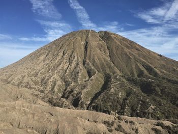 Low angle view of volcanic mountain against blue sky