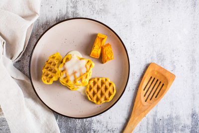 A stack of belgian homemade pumpkin waffles topped with sweet sauce on a plate on the table