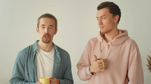 Portrait of young man holding coffee at home