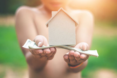 Midsection of child holding paper currency and model home