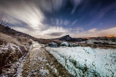 Scenic view of snow covered landscape against dramatic sky