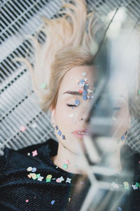 High angle view of woman with confetti on face lying on floor