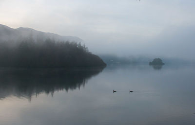 Scenic view of lake against sky during foggy weather