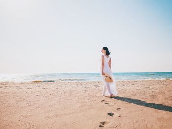 Woman walking on beach against clear sky