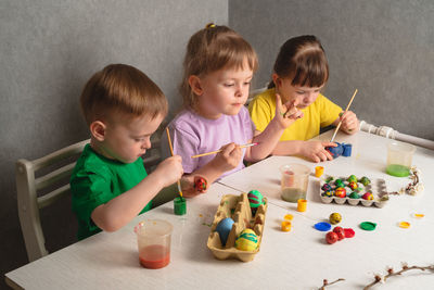 Children color eggs with food coloring. brother and sisters painting easter eggs.