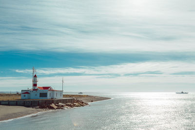 Lighthouse by sea against sky