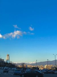 Cars on road in city against blue sky