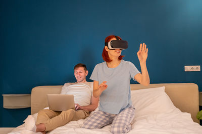 Portrait of young woman using mobile phone while sitting on bed at home