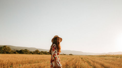 Portrait of woman standing on landscape against clear sky at sunset