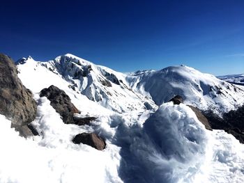 Scenic view of snowcapped mountains against clear blue sky