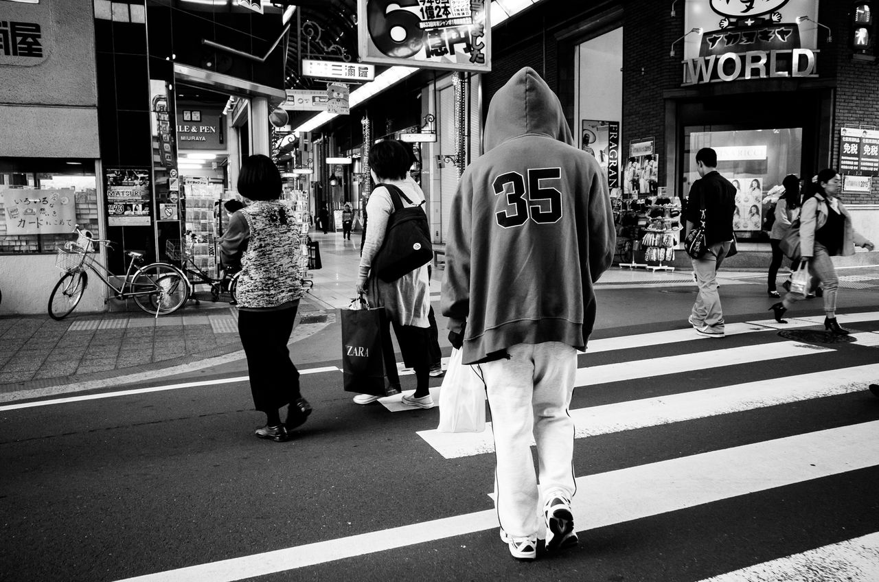 men, walking, person, street, lifestyles, city life, city, full length, transportation, large group of people, architecture, medium group of people, road, leisure activity, built structure, rear view, road marking, building exterior, group of people