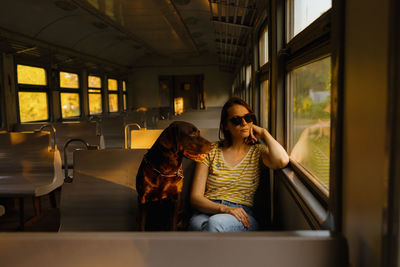 Woman and retriever dog ride a train, look out the window. traveling with a pet on public transport