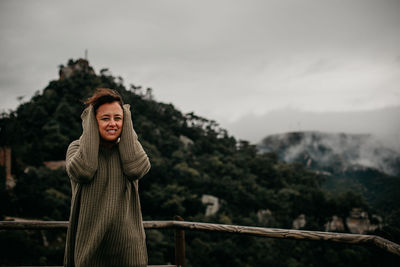 Woman standing by railing against mountain