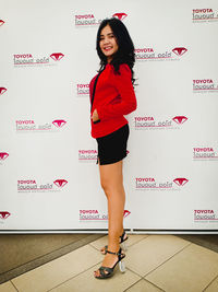 Full length portrait of woman standing against wall