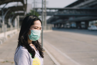 Side view of young woman wearing face mask while standing on road