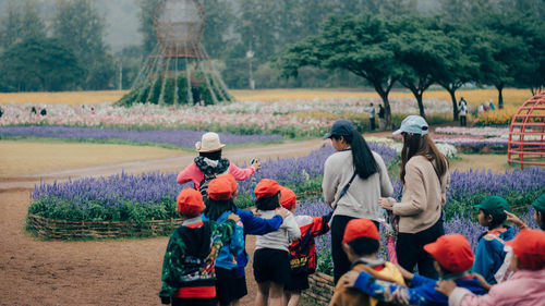 Students with teachers by flowering plants in garden