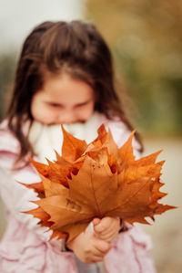 Close-up portrait of a girl with autumn leaves