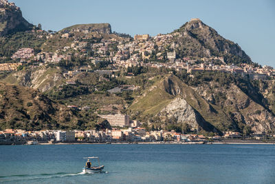 Boats in sea with mountains in background