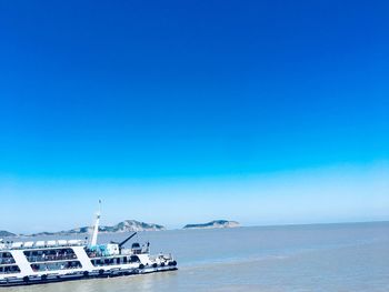 Boat in sea against clear blue sky
