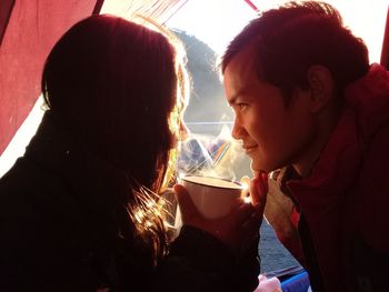 Couple having coffee while looking at each other in tent