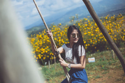 Young woman smiling while standing against plants