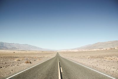 Empty road in desert against clear sky